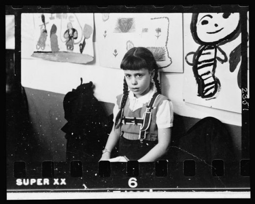 02-7.-Young-girl-half-length-portrait-standing-against-wall-displaying-art-work-in-classroom-in-Chicago-Illinois-520x416