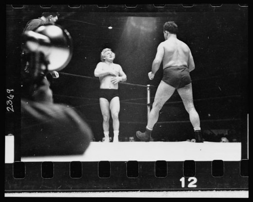 03-29.-A-wrestler-strides-toward-Gorgeous-George-who-stands-near-a-corner-of-the-ring-with-his-hands-on-his-chest-where-he-had-received-a-blow-in-the-previous-maneuver-in-the-wrestling-match-520x416