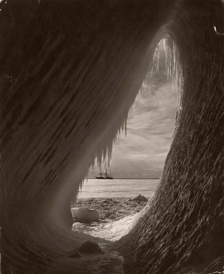 The sailing ship Terra Nova is framed by an ice grotto. Photograph by Herbert G. Ponting, National Geographic