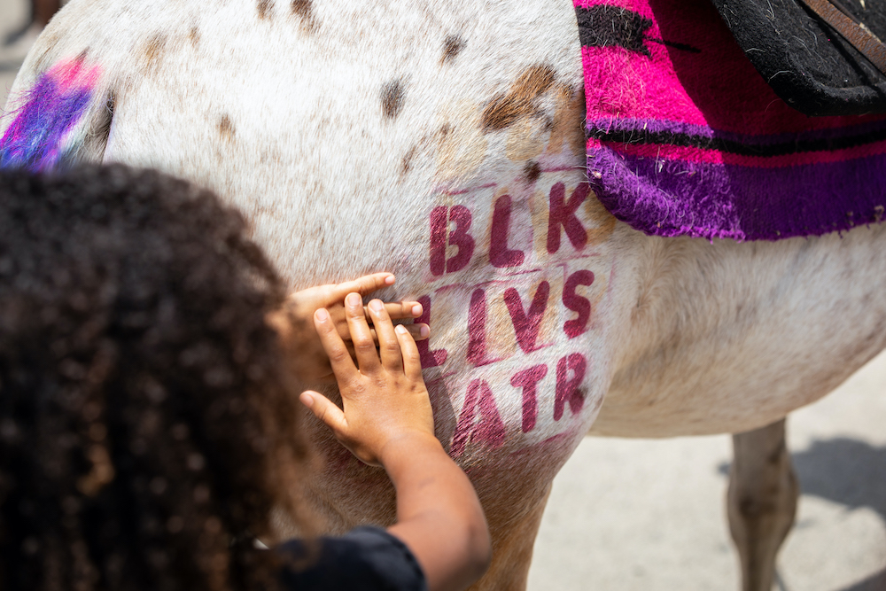  Laughs fill the air as children gather to pet the pink- and purple-tailed pony during the Juneteenth Festival in Leimert Park on June 19, 2020. Los Angeles, CA.