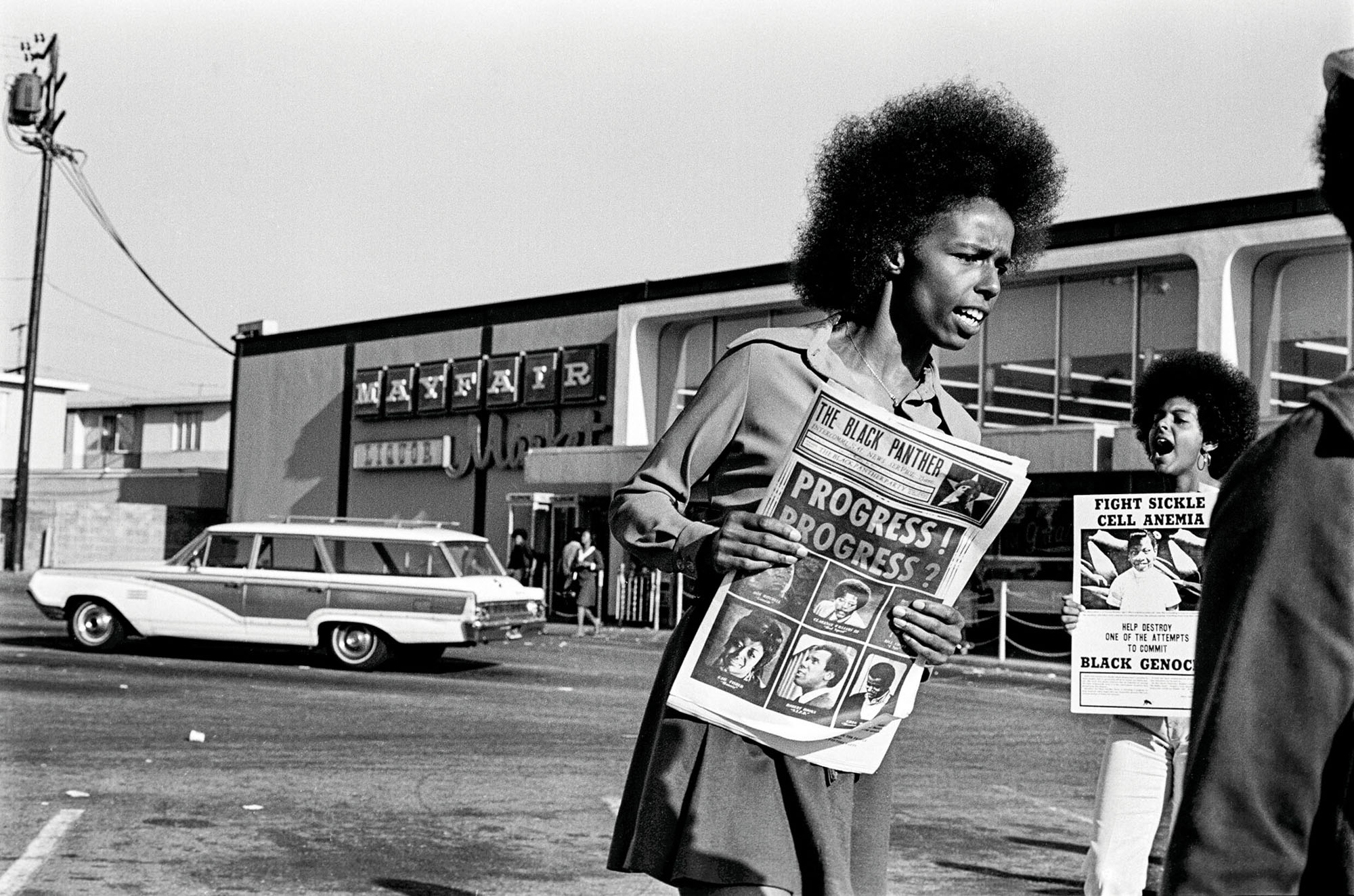 1971 - Oakland, California: Gloria Abernethy, woman of the Black Panther Party, sells the Black Panther newspaper at the Mayfair supermarket boycott. Tamara Lacey holds a Sickle Cell Anemia poster.